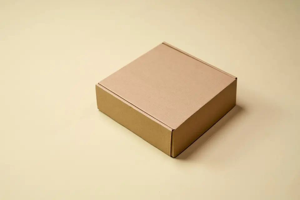 Small closed kraft box on a warm beige surface