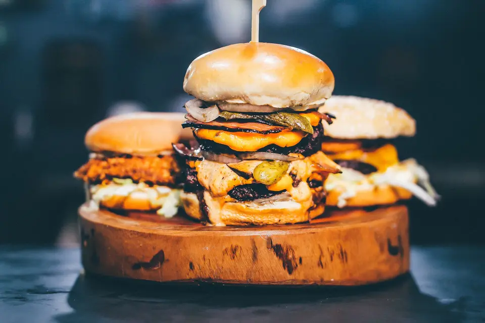 Three stacked burgers on a wooden board